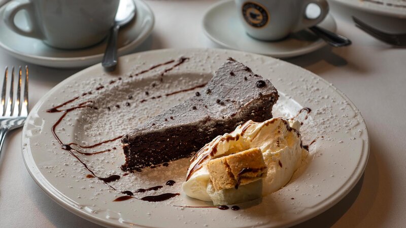 Chocolate cake dessert with whipped cream, powdered sugar and chocolate drizzle